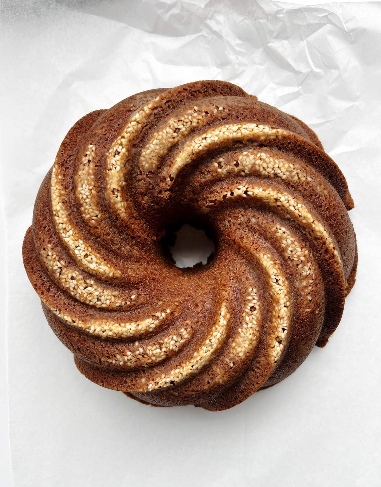 toasted sesame bundt cake on white parchment paper