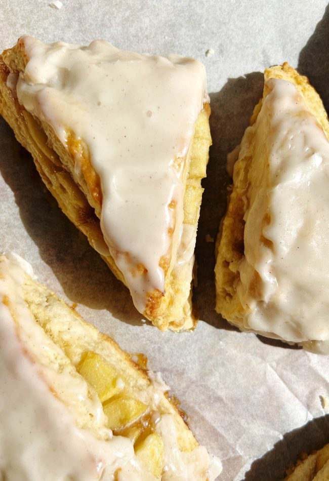 apple scones with glaze on parchment pape