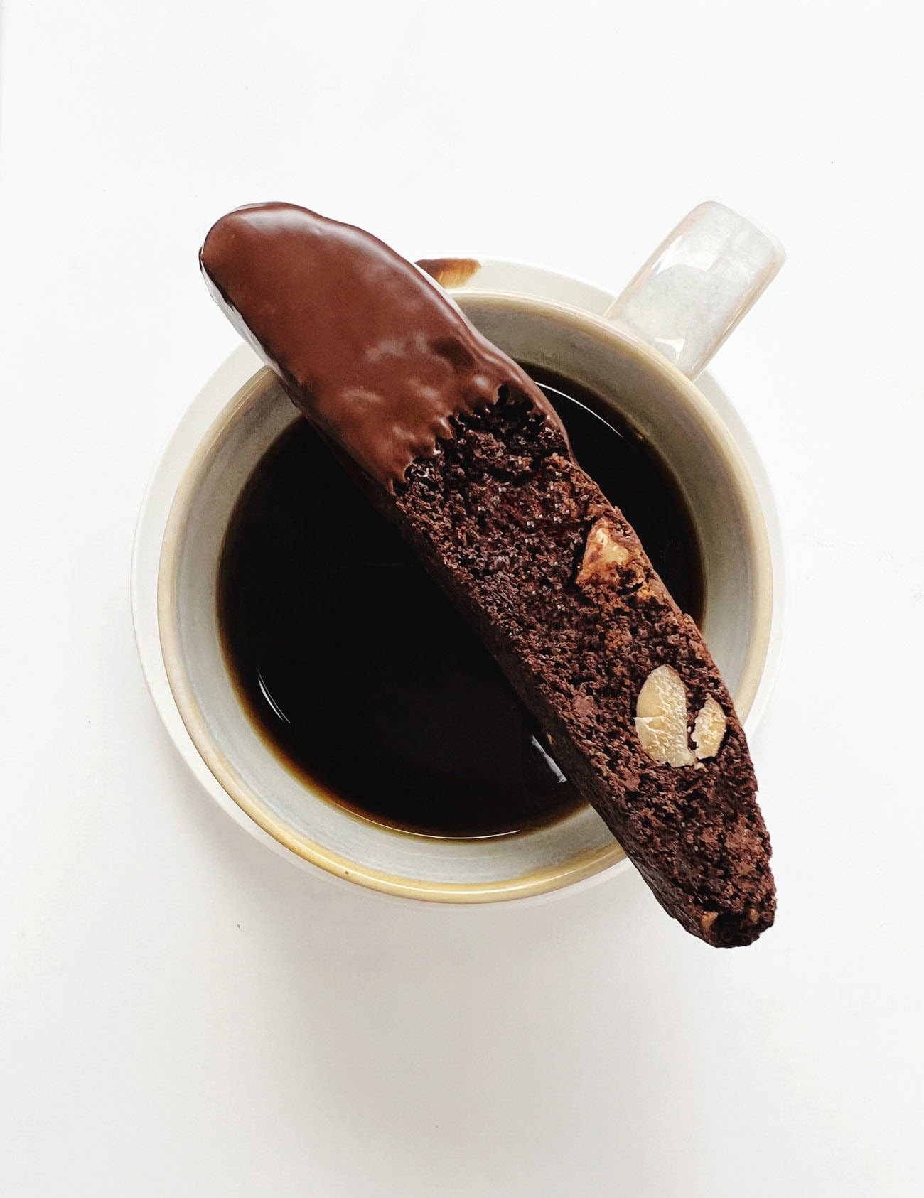 Chocolate dipped chocolate biscotti on top of cup of coffee